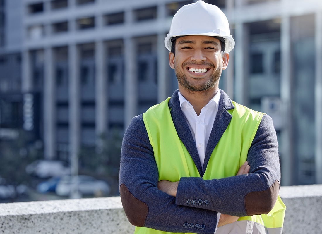 Insurance by Industry - Cheerful Construction Engineer With Hard Hat Standing at a Site on a Sunny Day